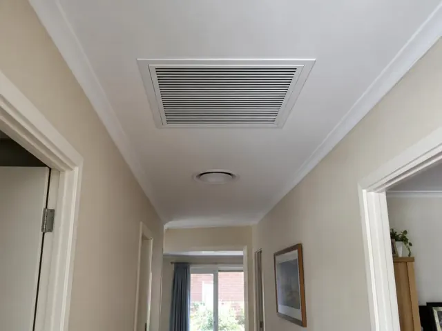 Ceiling return-air grille in a hallway with white walls and doorframes in Clearview