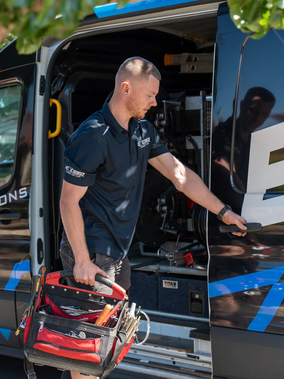 Technician lifting a tool bag from the back of the service van